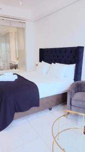 a bedroom with a large bed and a chair at Sandton Skye Executive Suite-2 in Johannesburg