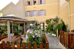 a patio with a table and flowers and a building at Hôtel du Fort in Meulan