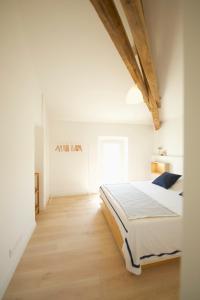a white bedroom with a bed and a wooden floor at Appartement - Loft Le Cosy in Hyères