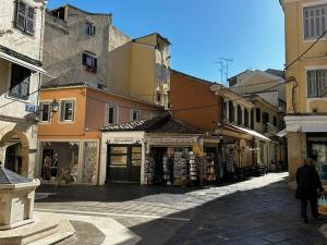 a man walking down a street next to buildings at Theodore's cosy apartment in Corfu