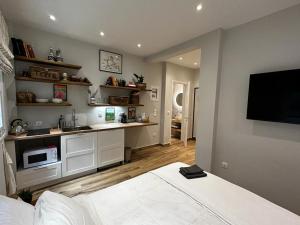 a room with a bed and a kitchen with a tv at Theodore's cosy apartment in Corfu