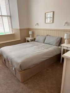 a large bed in a bedroom with two tables at 73 George Street. Appartment 1 in Oban