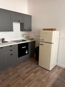 a kitchen with a white refrigerator and gray cabinets at 73 George Street. Appartment 1 in Oban