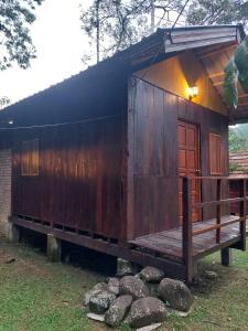 a small wooden cabin with a porch and a bench at Jungle Zen Janda Baik Campsite in Kampung Janda Baik