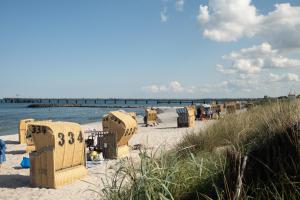ein Strand mit Stühlen und ein Pier im Hintergrund in der Unterkunft Ruhige Ferienwohnung 100 m zum Schönberger Strand mit Terrasse in Schönberger Strand