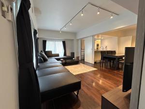 NIYS apartments 74 type في طوكيو: غرفة معيشة مع أريكة وغرفة طعام