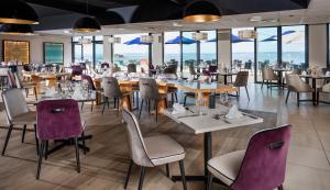 un restaurante con mesas, sillas y ventanas en Hôtel Valdys Thalasso & Spa - la Baie, en Douarnenez