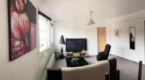 a living room with a tv and a couch and a chair at Bel appartement cosy très calme avec parking privé in Templemars