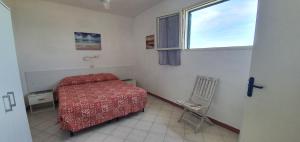 a bedroom with a bed and a window and a chair at Hotel Le Ghiaie in Portoferraio