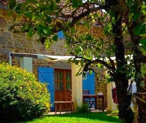 a house with a blue door and a bench in the yard at Domaine Charente - Cottage Charente in Mazières