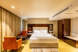 a hotel room with a bed and a desk at Citadel Sarovar Portico Bengaluru in Bangalore