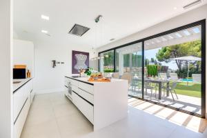 an open kitchen with white countertops and a large window at VACATION MARBELLA I Villa Chloe The Golfer, Infinity Pool, Rooftop Views, New-Built in Estepona