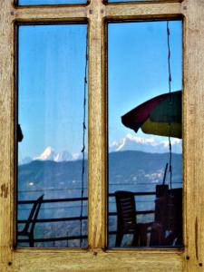 einen Blick auf die Berge durch ein Fenster in der Unterkunft KANAK RESIDENCY in Chālsa Mahābāri