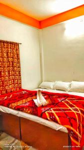 Schlafzimmer mit einem Bett mit einer roten Bettdecke in der Unterkunft KANAK RESIDENCY in Chālsa Mahābāri