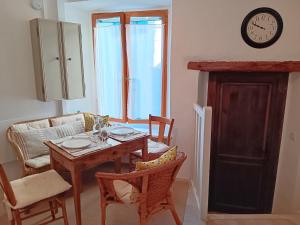 uma sala de jantar com mesa e cadeiras e um relógio em La Petite Romance - Gîte 3 étoiles em Siran