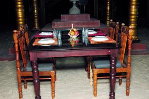 a table with a candle and a bowl of fruit on it at Elephant Courtyard- A Heritage Homestay in Alleppey