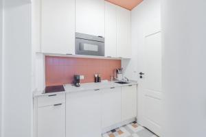 eine weiße Küche mit einer Spüle und einer Mikrowelle in der Unterkunft Modern apartment in City Centre in Danzig