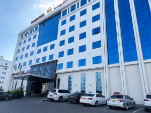 un grande edificio con auto parcheggiate in un parcheggio di ROZANA HOTEL a Mascate