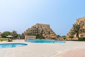 a resort with two pools and a building in the background at Amazing Studio with Balcony & Beach access-RAK in Ras al Khaimah