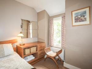 a bedroom with a bed and a chair and a mirror at Ty Nain in Caernarfon