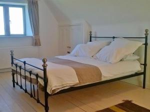 um quarto com uma cama com lençóis brancos e uma janela em Battens Farm Cottages B&B em Yatton Keynell