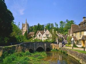 uma ponte sobre um rio numa pequena aldeia em Battens Farm Cottages B&B em Yatton Keynell