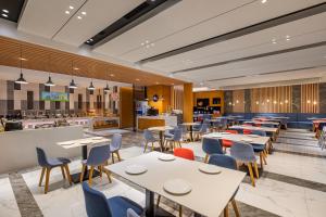 un restaurante con mesas y sillas y una cocina en Holiday Inn Express Xi'an Qujiang South, an IHG Hotel en Xi'an