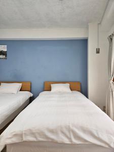 2 camas en un dormitorio con una pared azul en STAY ARI Kabukicho, en Tokio