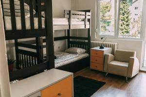 um pequeno quarto com beliches e uma cadeira em Smart hostel em Belgrado