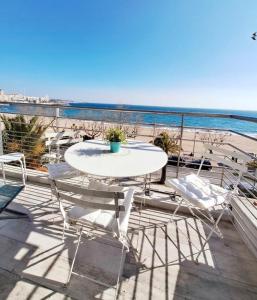 einen Tisch und Stühle auf einem Balkon mit Blick auf den Strand in der Unterkunft Le Panorama in Fréjus