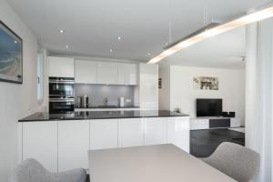 una cucina con mobili bianchi, tavolo e sedie di Schöne Parterrewohnung in Matten a Matten