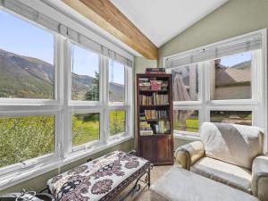 una sala de estar con ventanas, una silla y un estante de libros. en Woods25 Townhome Condo en Copper Mountain