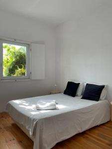 - un lit blanc dans une chambre avec fenêtre dans l'établissement Casa do Cristo Rei II, à Almada