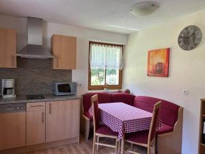 uma cozinha com uma mesa com cadeiras roxas e uma mesa e uma cozinha em Feichterhof em Riva di Tures