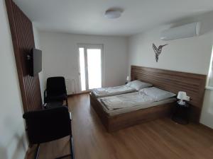 1 dormitorio con 1 cama y 2 sillas en apartmánový dom rodiny BÖJTÖS, en Virthova Pustatina