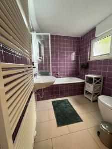 a purple tiled bathroom with a sink and a toilet at Altes Bauernhaus in der Natur in Detmold