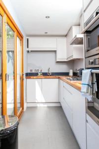 a kitchen with white cabinets and a window at Modern and Stylish 2 Bedroom House in Brighton in Brighton & Hove