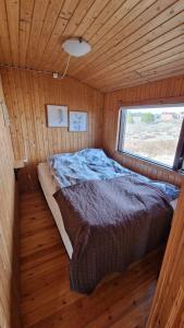 Cama en habitación pequeña con ventana en Thingvellir Lake Cottage, en Veiðilundur