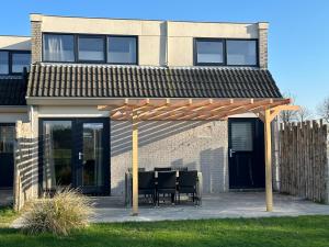 a wooden pergola in front of a house at 't Eibernest in De Cocksdorp