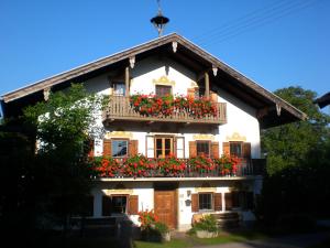 a white house with red flowers on the balcony at Ferienwohnung Schmuck Eva in Bergen