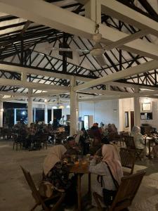 un grupo de personas sentadas en mesas en un restaurante en Dewa Daru Resort, en Karimunjawa