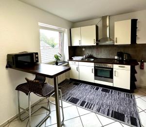a kitchen with white cabinets and a table and a microwave at BocholtApartments in Bocholt