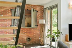 a living room with a brick wall and a window at Luxe, sfeervol en vrijstaand boshuis Chalet LaMast in Norg