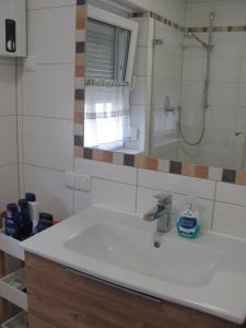 La salle de bains est pourvue d'un lavabo blanc et d'une douche. dans l'établissement #2 Ruhiges gemütliches Ferienzimmer mit zusätzlichem Schlafsofa Gemeinschaftsbad W-Lan Airport nah Late Night Check in, à Trunkelsberg