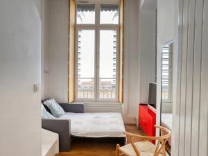 Cette petite chambre comprend un lit et une fenêtre. dans l'établissement Palace Opéra, studio de charme, à Lyon