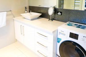 a bathroom with a washing machine and a sink at Petit Verdot Cottage - A Vineyard Retreat in Barossa Valley in Rowland Flat