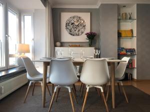 a dining room with a wooden table and white chairs at Modern apartment at 2 steps from beach in Ostend