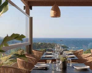 a long table in a restaurant with a view of the ocean at Irida Hotel Agia Pelagia in Agia Pelagia