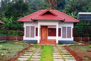 ein kleines Haus mit rotem Dach in der Unterkunft Himani Heritage Resorts, formerly Camp Nishani Holidays in Madikeri