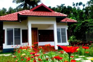 ein kleines Haus mit vielen Blumen davor in der Unterkunft Himani Heritage Resorts, formerly Camp Nishani Holidays in Madikeri